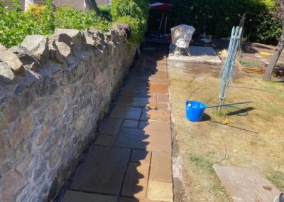 Freshly laid tiled pathway against stonewall