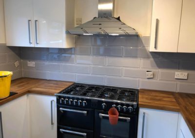 New kitchen with oven, grey tiles and wooden counter top
