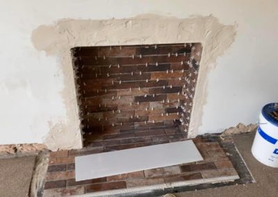 Fireplace tiling with tile spacers and fresh repaired plaster