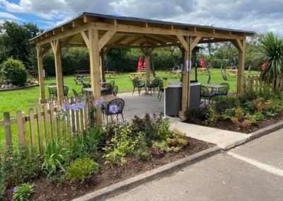 Large wooden gazebo with outdoor chairs and tables